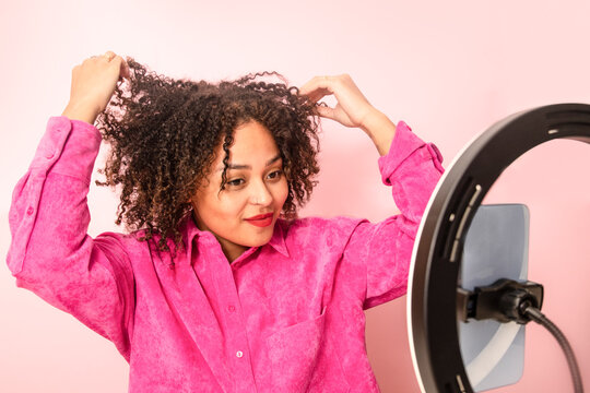 Calm ethnic woman demonstrating hairstyle during beauty tutorial