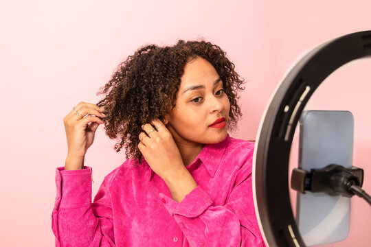 Calm ethnic woman demonstrating hairstyle during beauty tutorial