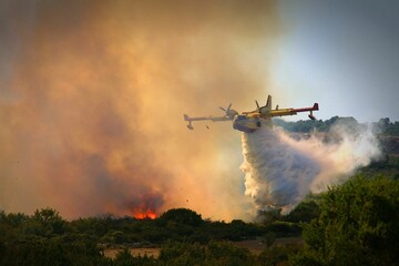 Closeup shot of a plane flying above the forest in fire in Canada