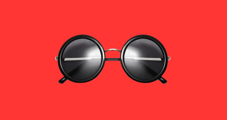 Stylish black round sunglasses isolated on red background