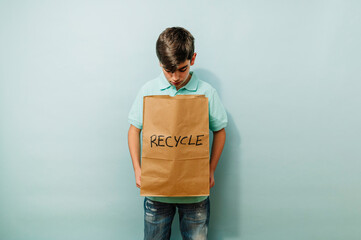 Young boy recycling with paper bag in studio.
