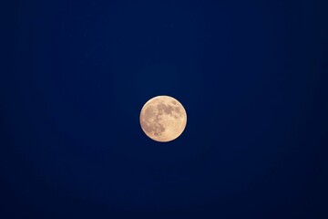 Beautiful closeup of a full moon on a blue sky background
