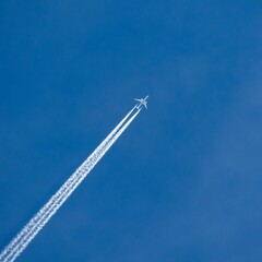 Low angle shot of an airplane flying in a blue cloudless sky