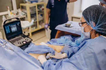 A phlebologist performs an ultrasound of the legs for varicose veins using a modern