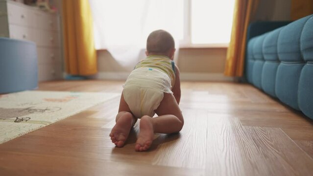 baby newborn crawling on the floor. happy family kindergarten kid concept. First steps, baby crawling view from the back. baby learns to crawl to explore the world dream. lifestyle first steps creeps
