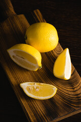 Lemon slices on a wooden cutting board. Juicy tropical fruit on a dark background