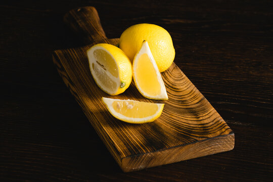 Lemon slices on a wooden cutting board. Juicy tropical fruit on a dark background