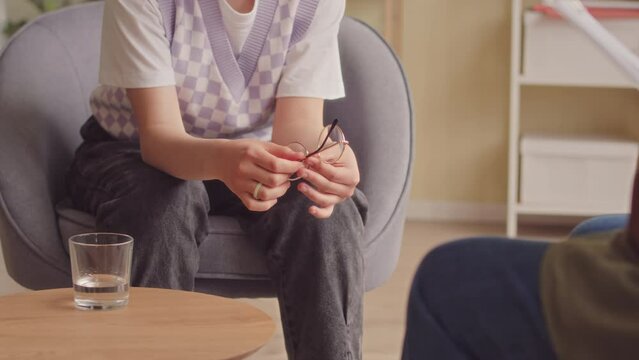 14 year old Caucasian teenage girl getting nervous while having conversation with psychology specialist in office