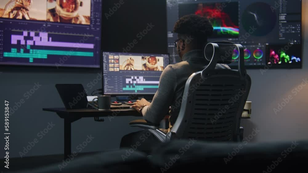 Poster african american colorist makes color grading in video editing software. multiple monitors with spac
