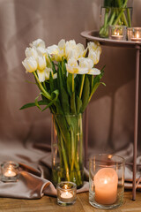 Candlelight decor near table for couple on Valentine's day. Luxury romantic date. Decoration tulips flowers, decor candles. Location for surprise marriage proposal.
