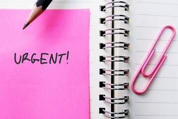 Pink note and paper clip with text written URGENT, concept of very important state or situation...