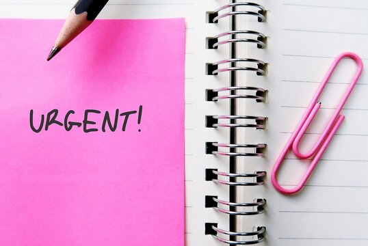 Pink note and paper clip with text written URGENT, concept of very important state or situation which require action or attention immediately
