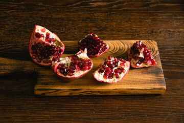 Pomegranate pieces on a cutting board on a dark background