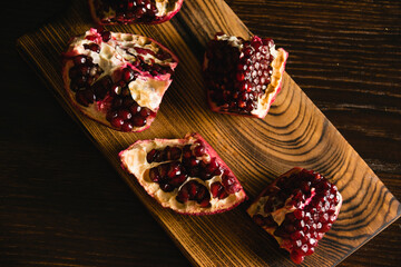 Pomegranate pieces on a cutting board on a dark background