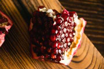 Appetizing piece of sweet pomegranate macro on cutting board on dark background