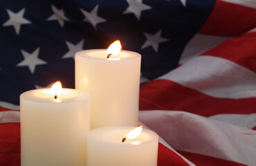 Fototapeta na wymiar Burning candles on wavy US flag background. Memorial day concept. 