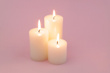 Obraz na płótnie Canvas Candles with different size melting and burning on pink background. 