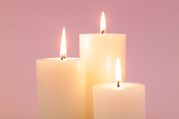 Obraz na płótnie Canvas Close up of candles burning on pink background.