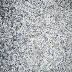 A texture of small stones in a gray-blue tone, the old rough wall of a thick column in the street. Random pattern
