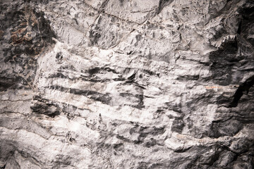Stone texture of an old rough building wall with cracks, reliefs, plots. Random pattern