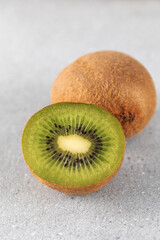 Green ripe kiwi half and whole on grey table. Place for text. Horizontal photo.