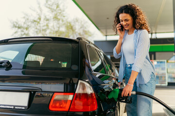 A young woman talks to her boyfriend, a family member, on the phone and fills her car with fuel
