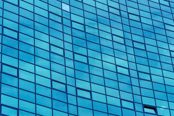 Fototapeta na wymiar Fragment of a modern office building. Abstract geometric background. Part of the facade of a skyscraper with glass windows.