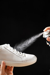 Applying a water-repellent hydrophobic spray to white women's sneakers. Protection of shoes from...