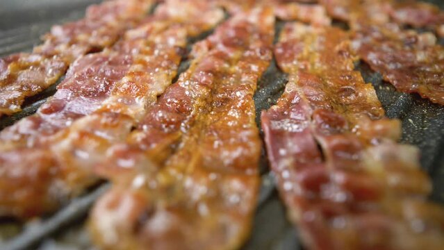 Strips of Bacon sizzling in the grill plate, focus transition, close-up view