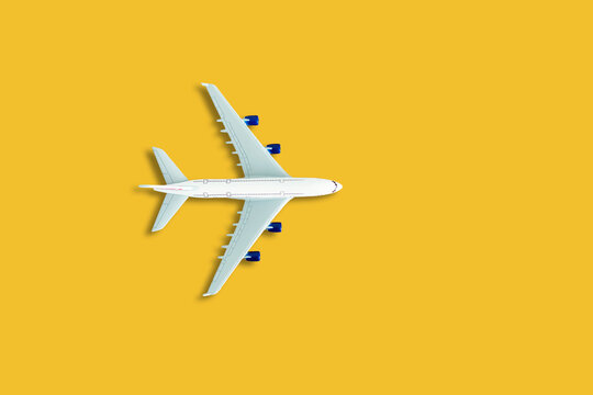 Flat lay design of travel concept with plane on yellow background with copy space.