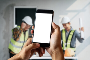 Engineer hand held black phone with a blank white screen in the office in the morning light.