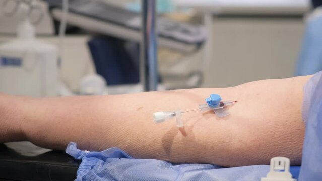The doctor inserts a needle into a vein and attaches a drip.