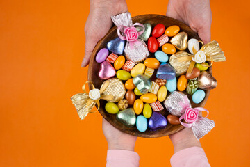 Holding bowl of sweet, woman and child hands holding bowl of sweet. Top view image of wrapped...