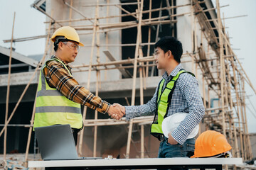 construction worker wearing a protective helmet and vest is holding his colleague's hand while...
