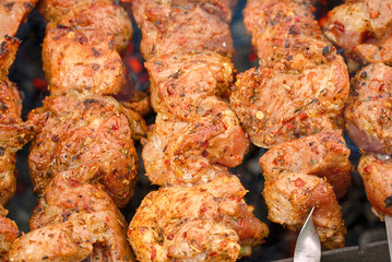 Grill barbecue meat on brazier with smoke. Cooking meat on brazier. Meat sticks cooked at barbecue, close up. Shish kebab cooking outdoors..