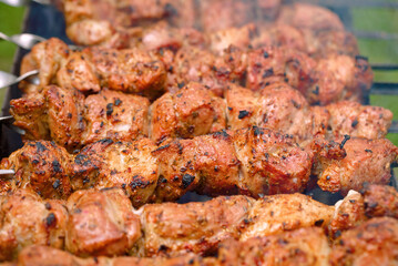 Roasted meat cooked at barbecue, closeup. Spicy marinated meat cook on bbq grill. Pork meat, shashlik, prepared on grill outdoor. Shish kebab cooking outdoors..