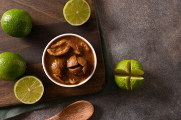 Home made Sri Lankan Lime Pickle of lime, salt, chilli, pepper on brown background. View from...