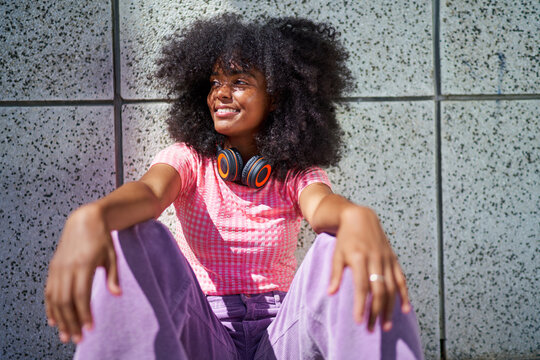 Portrait happy, cool young woman with headphones at wall