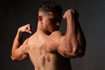 Athlete bodybuilder trains in the studio in the rain.
