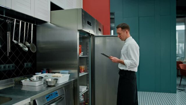 Professional chef using tablet computer for recipes while working in modern kitchen cooking concept