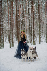 Pretty girl with dogs in forest at winter