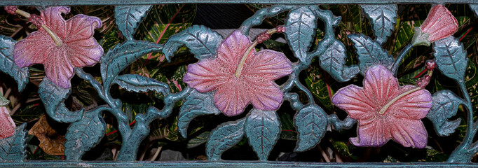 Painted cutout of metal flowers and leaves design on gate