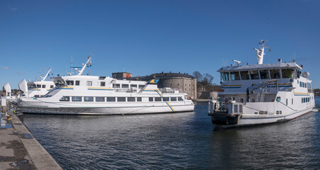 Commuter archipelago ferries moored at a pier in the archipelago town Vaxholm one ferry arrives,...
