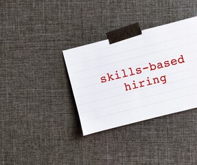 Stick note on office wall with text written Skills-based Hiring - refers to practice of employers...