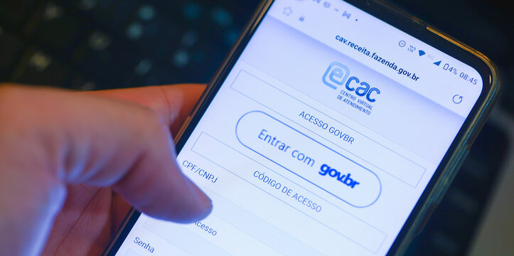 Um homem com um telefone celular mostrando a plataforma e-CAC que &eacute; o Centro Virtual de Atendimento ao Contribuinte da Receita Federal do Brasil. Bras&iacute;lia, DF - Brasil. 05/04/2023.	