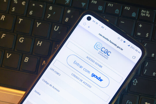 Um telefone celular sobre um teclado de um laptop mostrando a plataforma e-CAC que &eacute; o Centro Virtual de Atendimento ao Contribuinte da Receita Federal do Brasil. Bras&iacute;lia, DF - Brasil. 05/04/2023.	