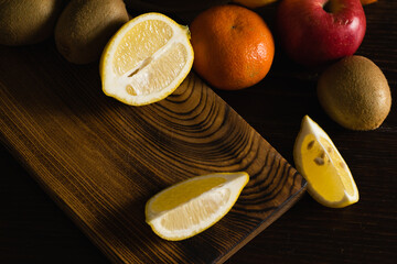 Fruits on a cutting board on a dark background. Juicy sliced lemon flatlay
