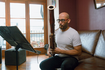 young latino man playing the bassoon at home