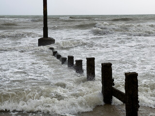 Damaged breakwater groynes useless against longshore drift and storm surges caused by sea level rises and climate change.
