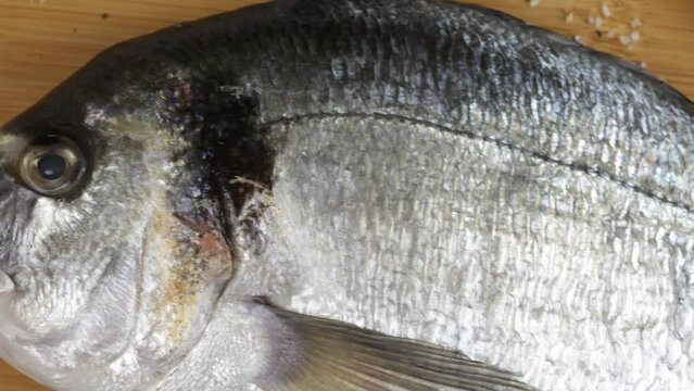 daurade enti&egrave;re, en gros plan, sur une planche &agrave; d&eacute;couper